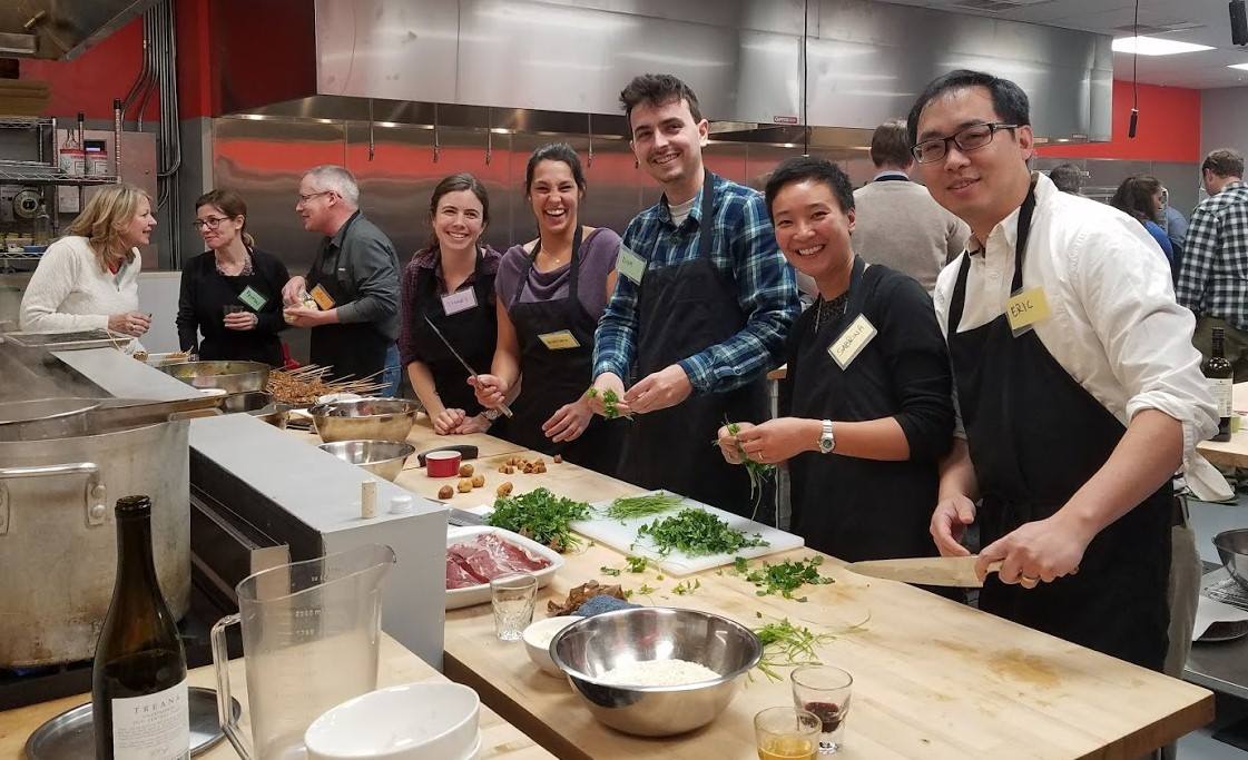 a group of people standing in a kitchen preparing food