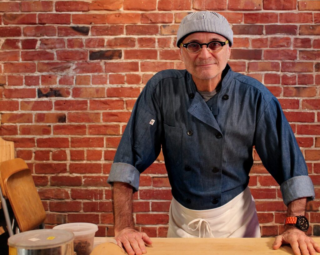 a man standing in front of a brick wall