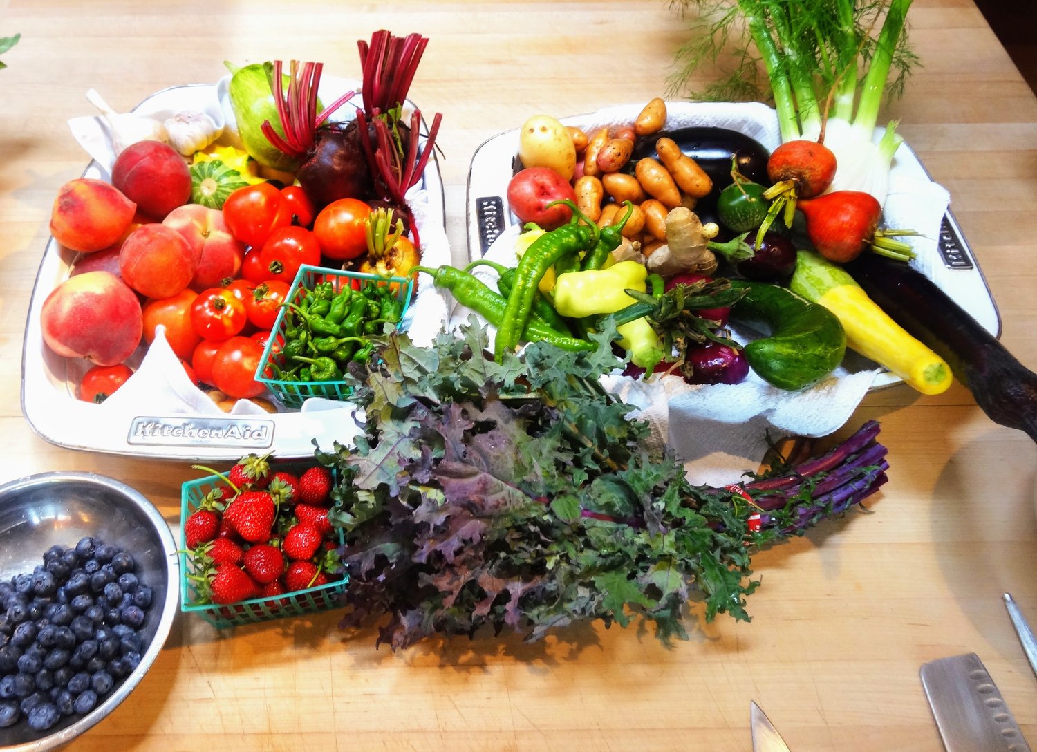 a wooden table topped with lots of fresh fruit and vegetables on display